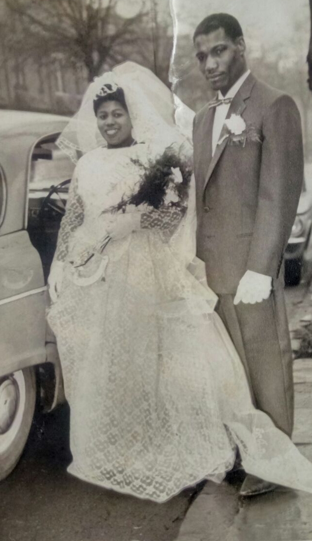 Black and white photograph of a couple of Carribean heritage in their wedding outfits.