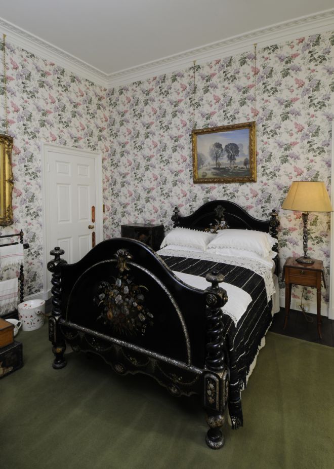 Black japanned double bed with curved head and footboard inlaid with a flower design.
