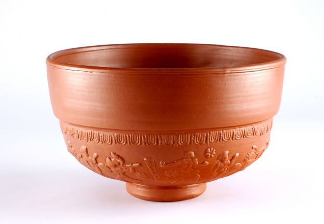 A large terracotta Roman bowl with images of people embossed around the base.
