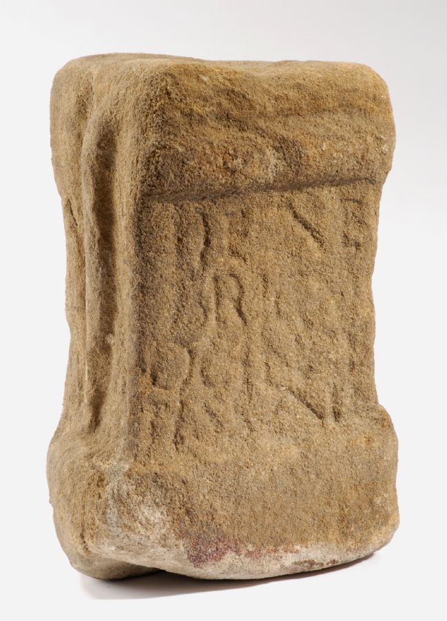 A worn stone altar made from a pale stone (maybe sandstone).  The inscription on it is quite faint.