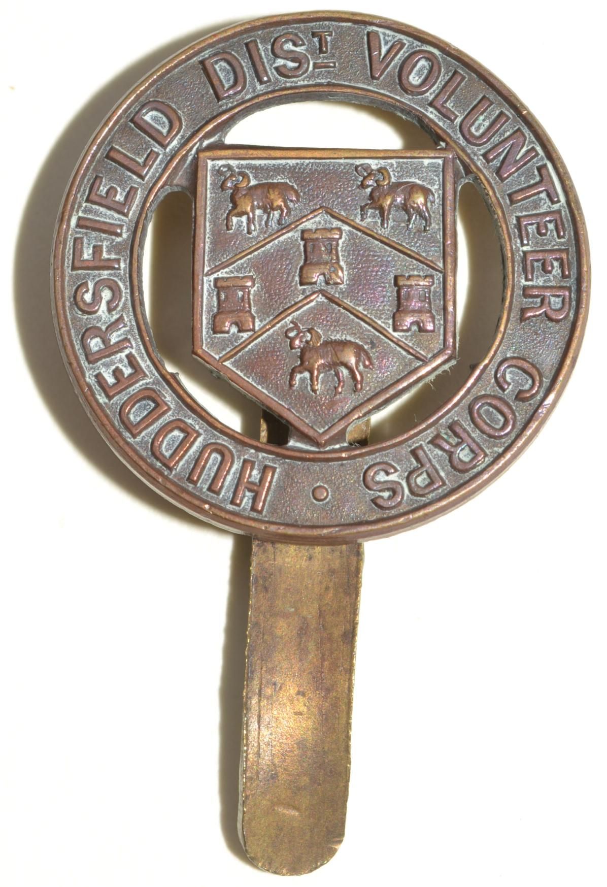 Bronze badge with a shield featuring sheep and towers, encircled by "Huddersfield Dist. Volunteer Corps".