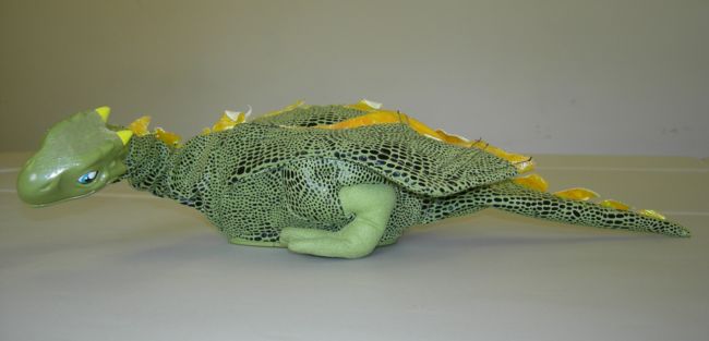 Norbert the dragon has his eyes open and tail out straight.  He is green with darker scales and a yellow trim to his wings.