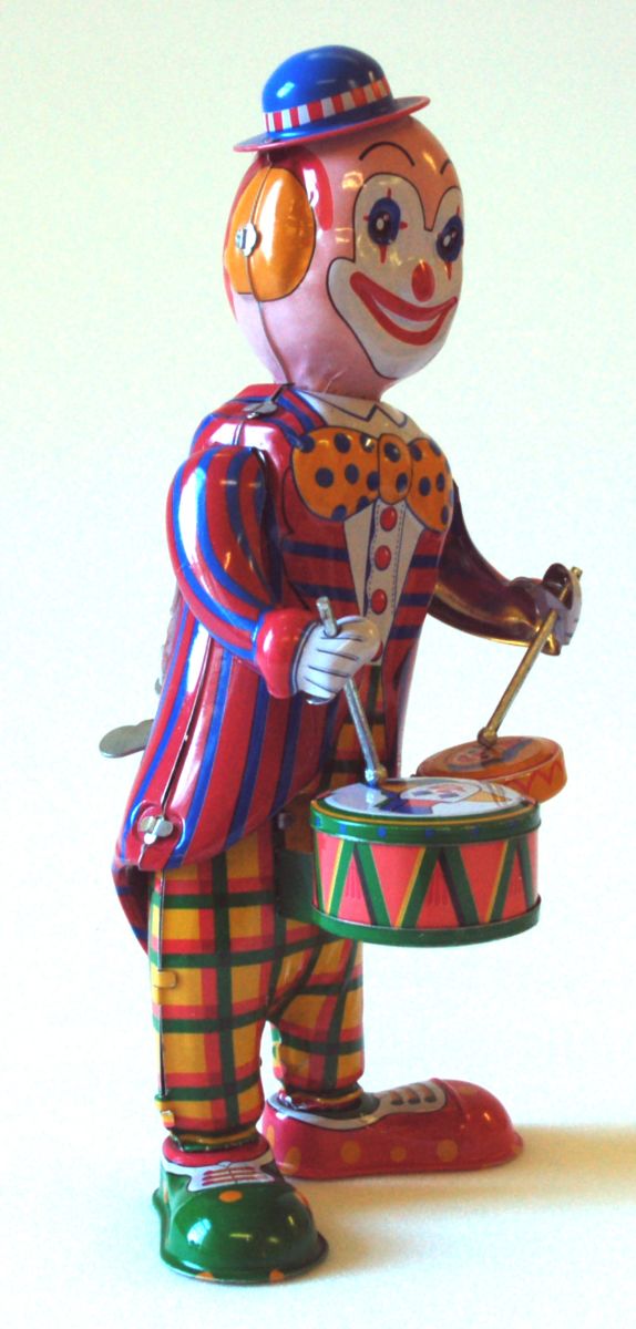 Modern, Brightly Coloured clockwork toy clown.  he wears a blue and red striped jacket, yellow, green and pink checked trousers,  He has a blue bowler hat on his head and two drums and drumsticks.