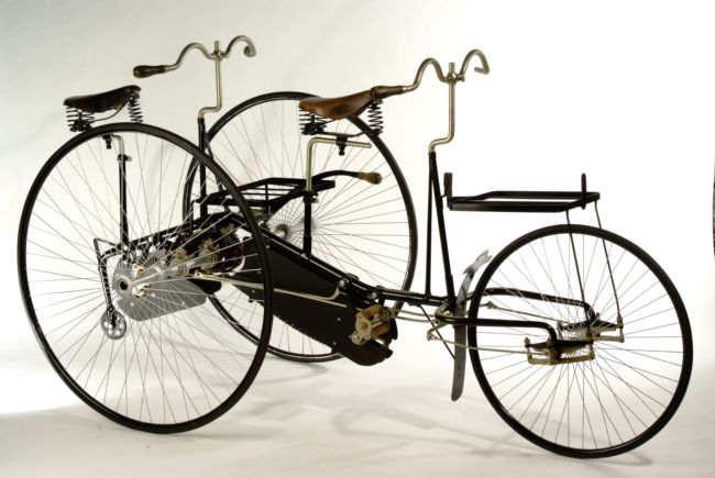 The Tandem Tricycle, a 3 wheeled cycle for 2 people.  there are two wheels at the back and one at the front.