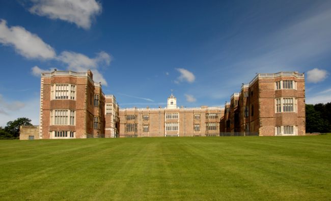 Large, red brick building with a wing at each end of a central building extending forward.