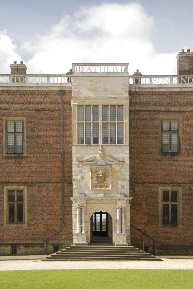 Entrance is made from a lighter stone with a pillar either side of the wide door.  Above the door is a crest.