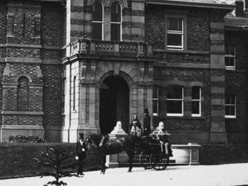 Black and white photo of Whinfield House, Preston showing a grand entrance with a horse drawn carriage and footman waiting outside.