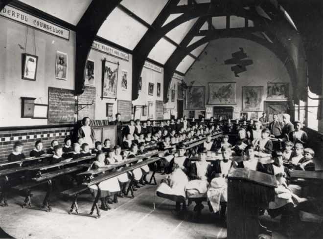 A very large classroom full of children in rows at desks