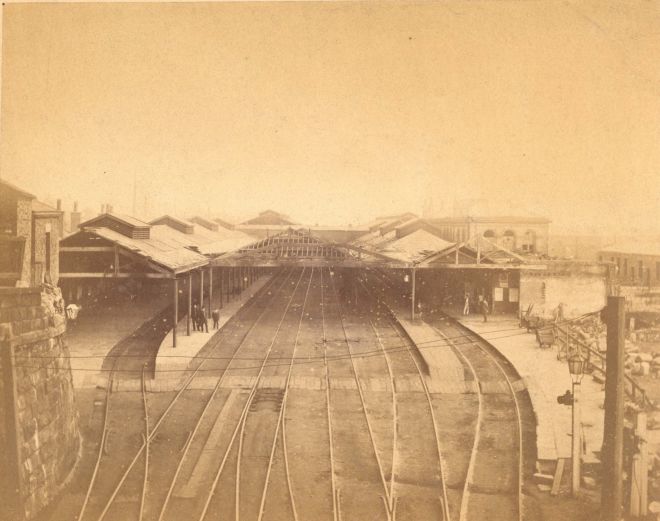 Black and white photograph of multiple train tracks running into a station