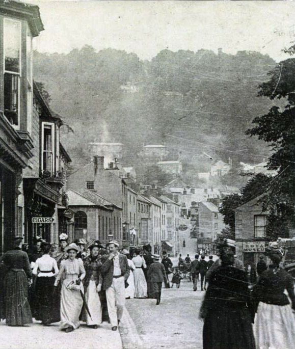Black and white photograph showing a busy street, filled with people