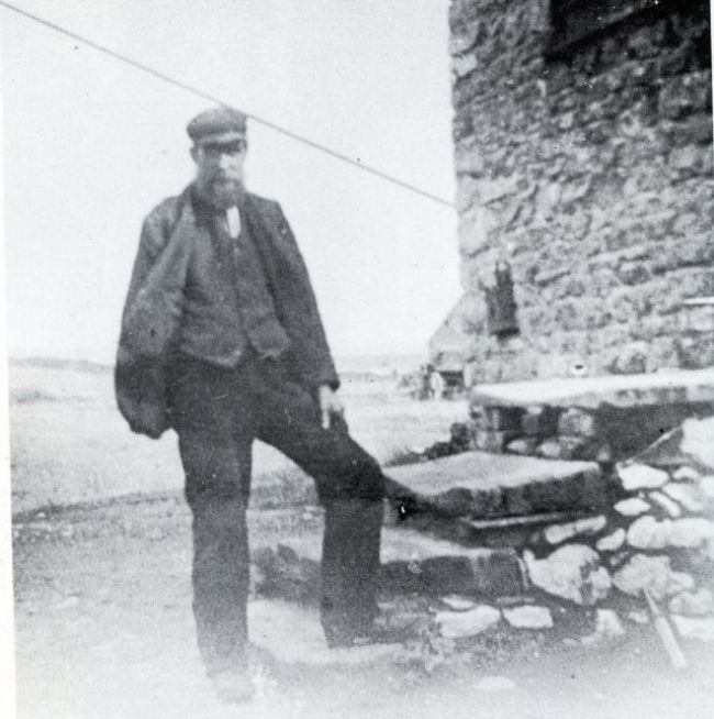 A photograph of a miner standing outside a mine, 1800s.  He is wearing a soft cap and has a beard
