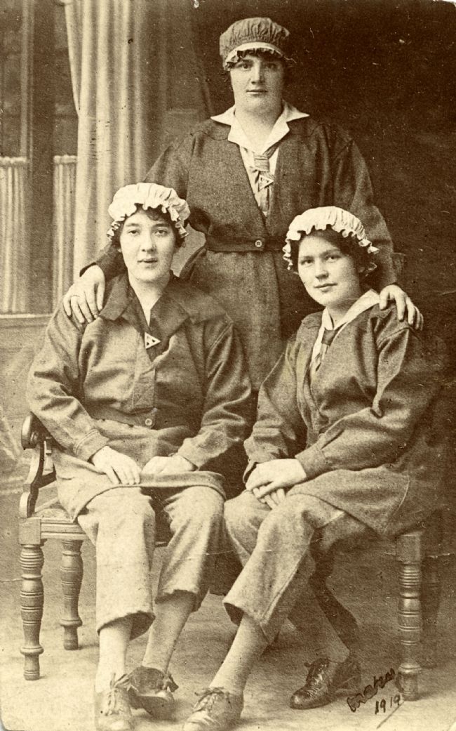 Female Hull munitions workers wearing their uniforms and triangular 'On War Service' badges