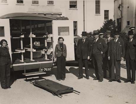 Photograph showing female stretcher bearers standing outside the back of an open ambulance