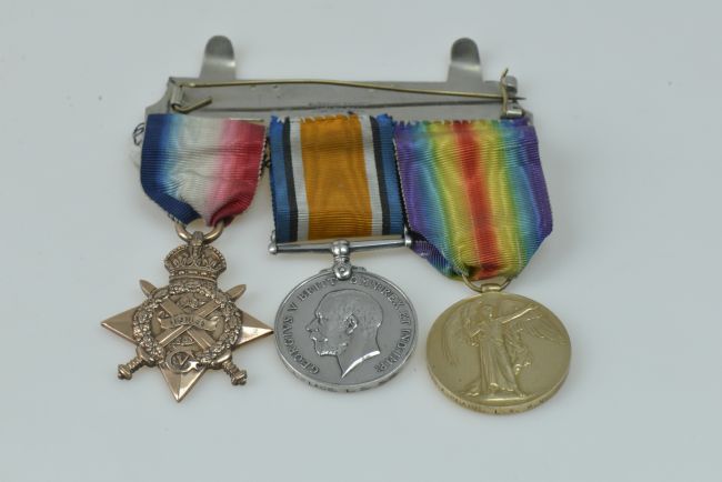 Three different gold and silver WW1 medals attached to colourful ribbons