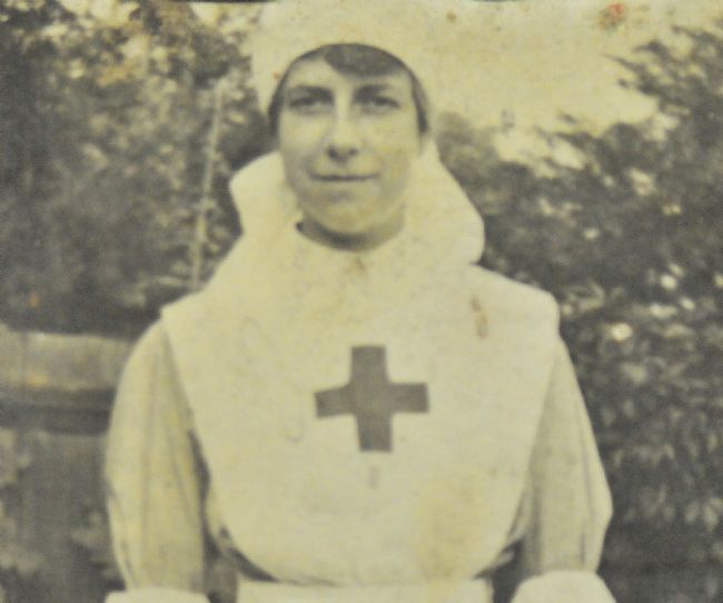 Phyllis Tessier wearing her WW1 nurses uniform of whtie apron with a cross on the front and white cap
