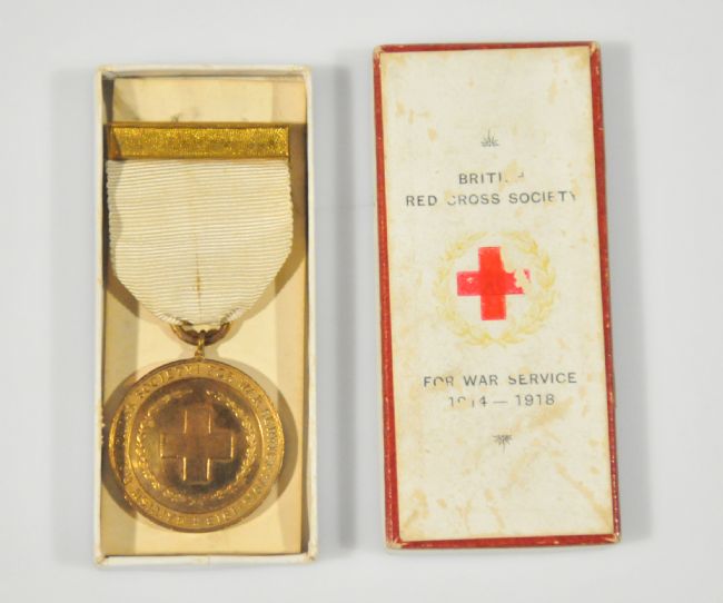 Gold WW1 Red Cross Medal, shown next to its box. The medal has a white ribbon