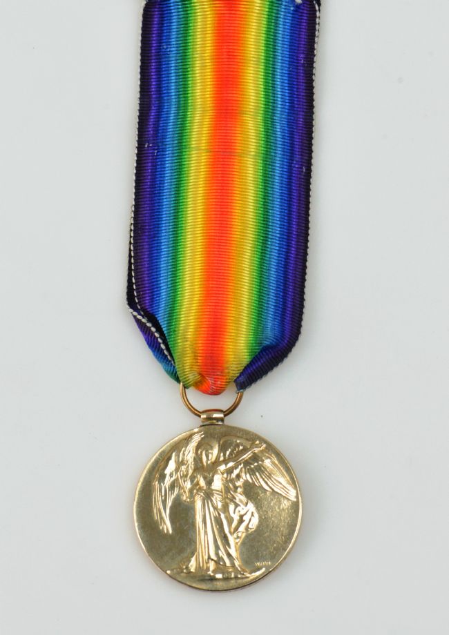 Gold coloured medal with an image of winged Victory.  Rainbow ribbon