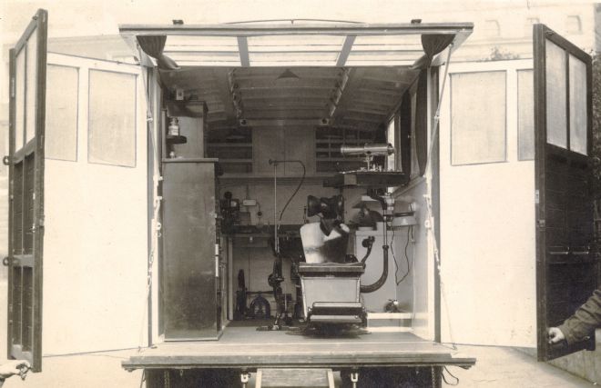 View of the inside of the mobile dental surgery, showing a chair on the right and cabinets and equipment on the left and back wall.