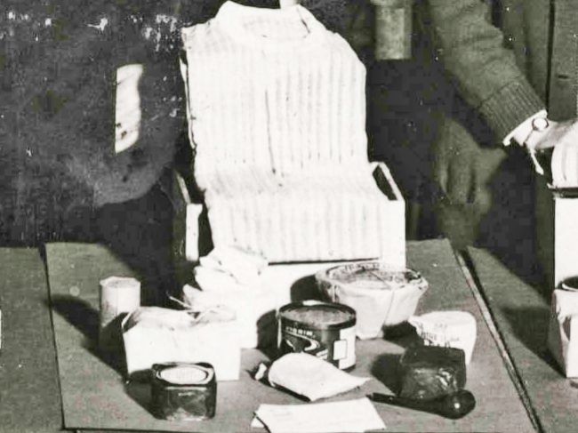 Boxes about to be sent to prisoners in Germany, showing a shirt, pipe, and varioius tinned items.