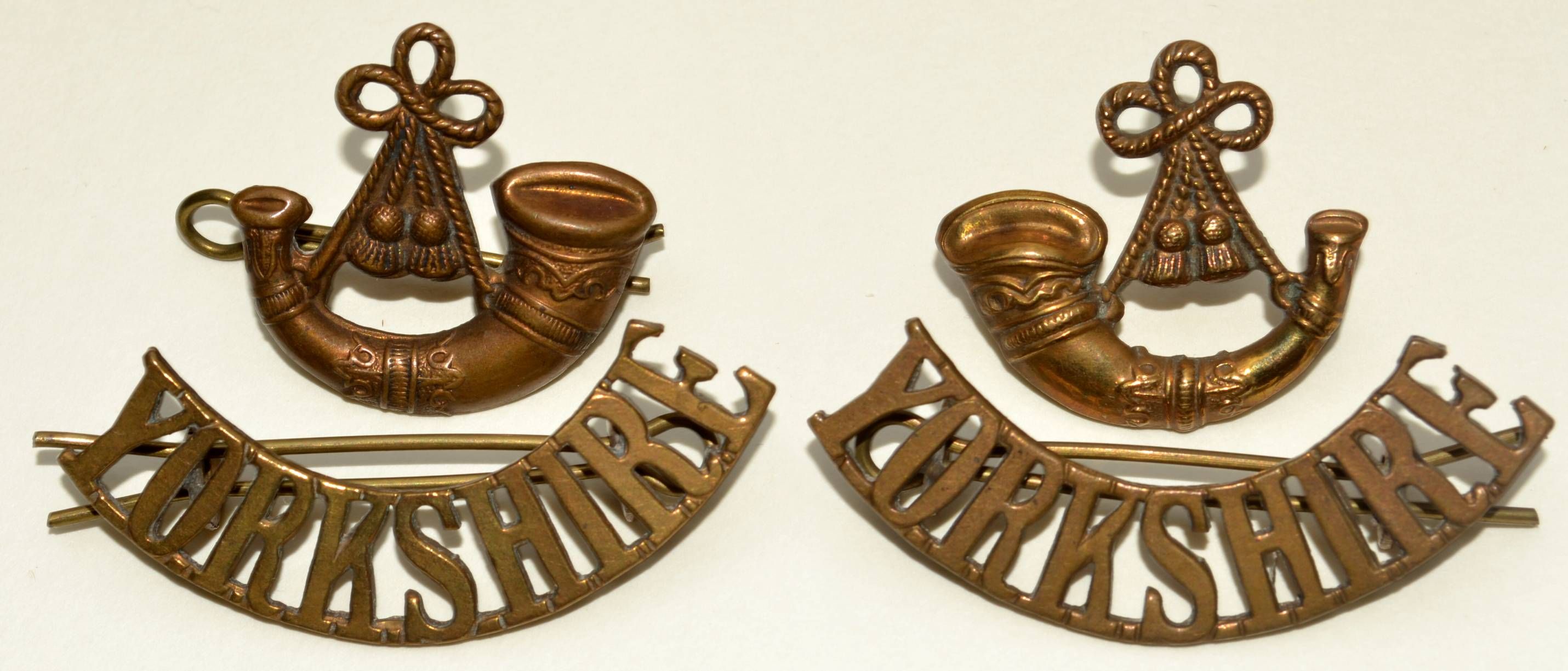 A pair of bronze World War II military collar badges from the King’s Own Yorkshire Light Infantry, each featuring a hunting horn above a curved scroll inscribed with the word “Yorkshire”.