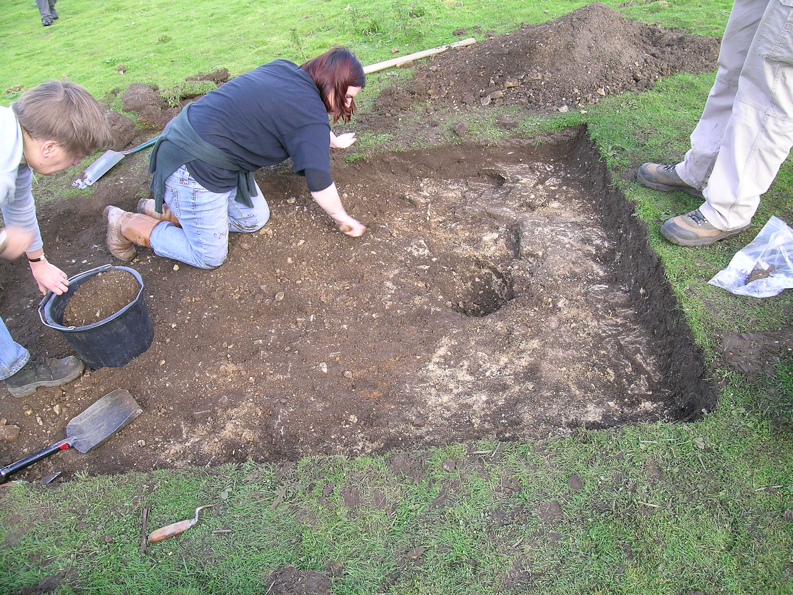 Colour photograph showing arcaheologists digging in an open pit.