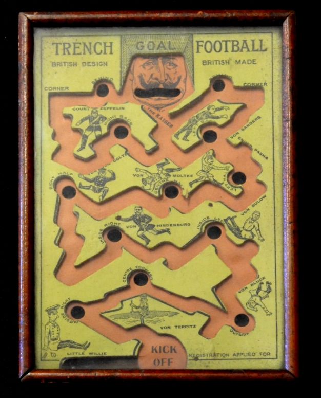 A vintage tabletop game titled “Trench Goal Football” featuring caricatures of World War I German military figures such as the Kaiser, Hindenburg, and Von Bülow. The game board has maze-like paths and holes labeled with these names, ending at a goal under the Kaiser’s face.