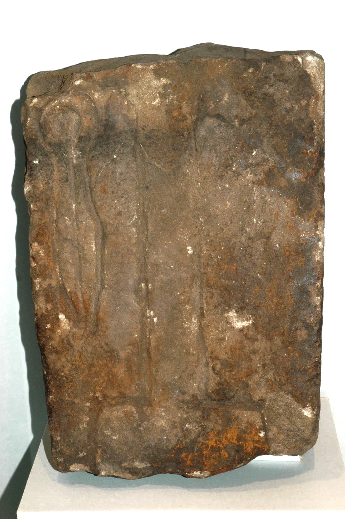 A rough, weathered stone tablet with faint carvings, with brown and gray tones.