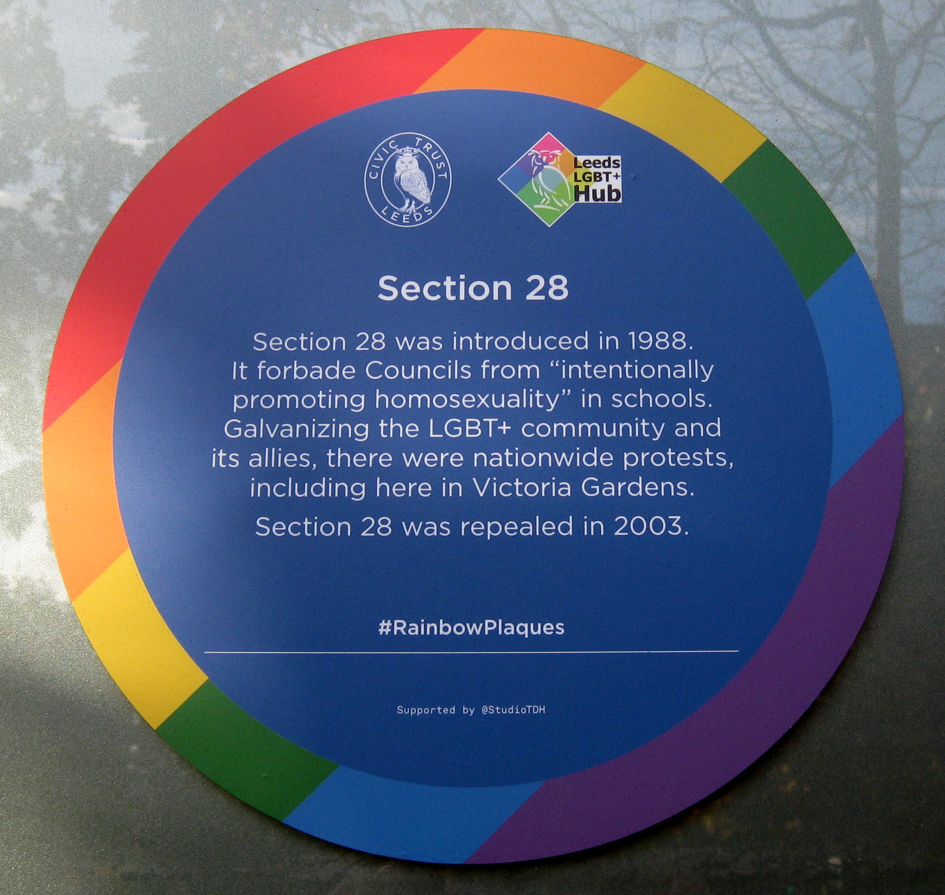 Colour photograph of a blue plaque with a rainbow edge
