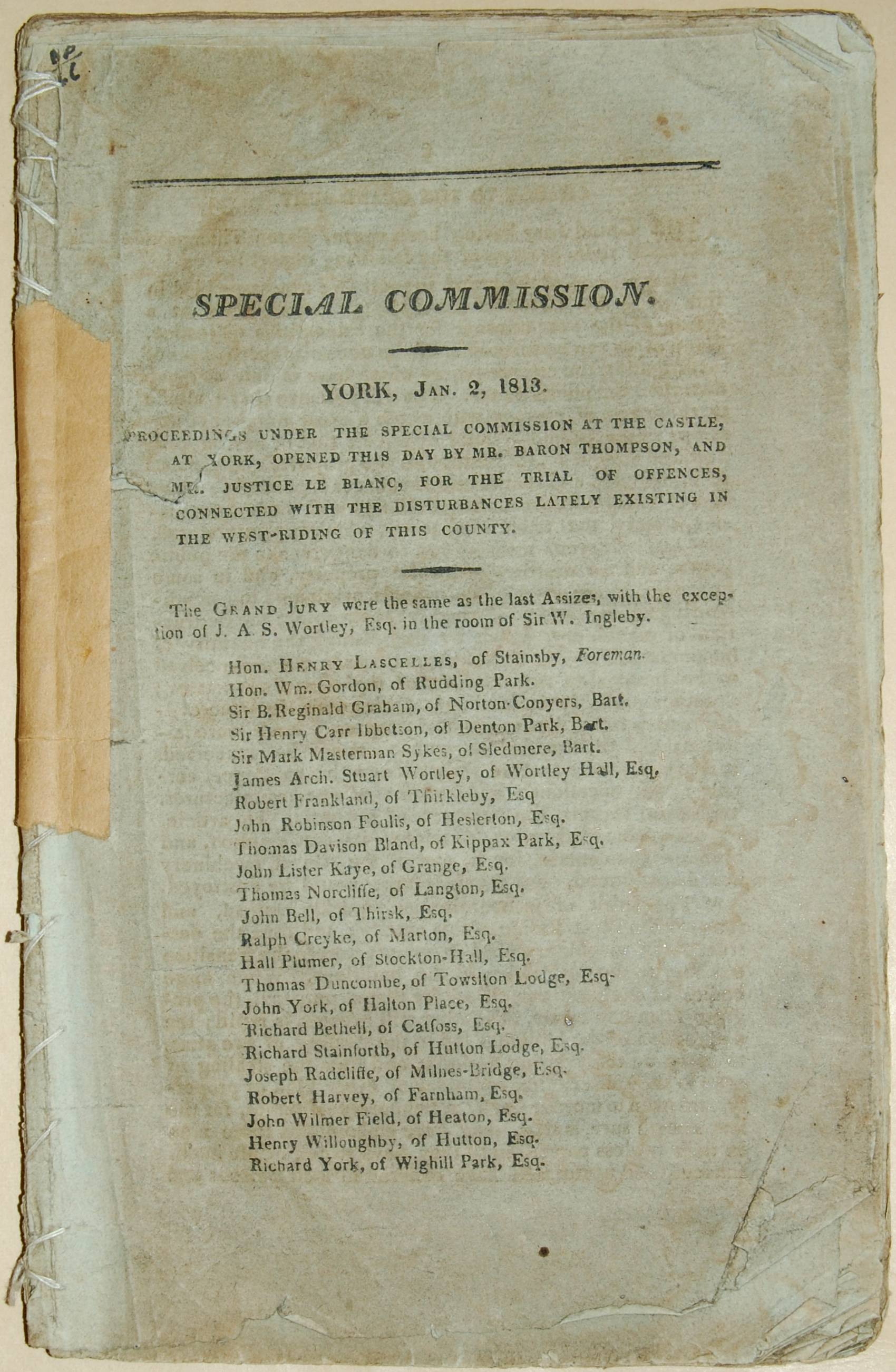 Faded, worn, and slightly torn historic document page titled 'Special Commission' dated 2 January 1813, from York Assizes. The page shows typed text detailing trial proceedings of Luddite prisoners for disturbances in West Riding, with a list of Grand Jury members. The paper has visible creases, discolouration, and a taped repair on the left edge.