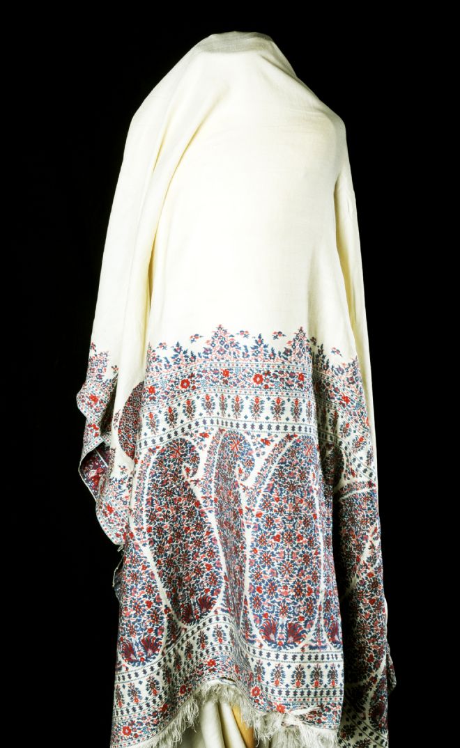 The top half of the shawl is plain white or cream and the bottom half has a red, blue and pink paisley design on it.