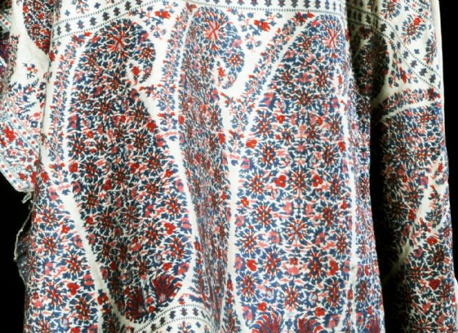 Close up of the pattern in red, blue and pink shows small flowers grouped together in kidney-shapes