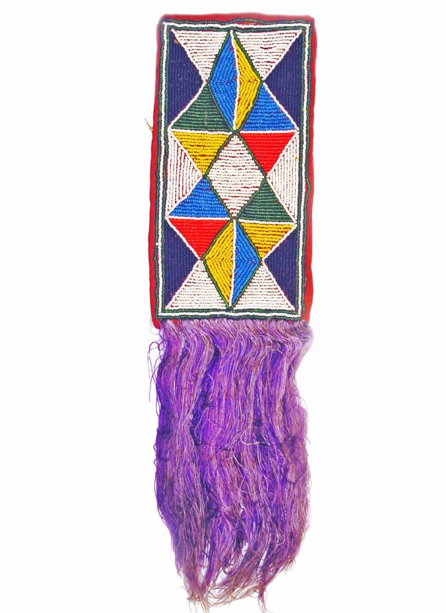 Rectangular beaded mat with purple tassles at one end. Design is made up of triangles in light and dark blue, white, red, yellow and green beads.
