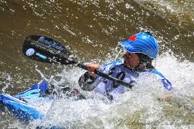 Colour photograph showing a woman in a canoe in white water