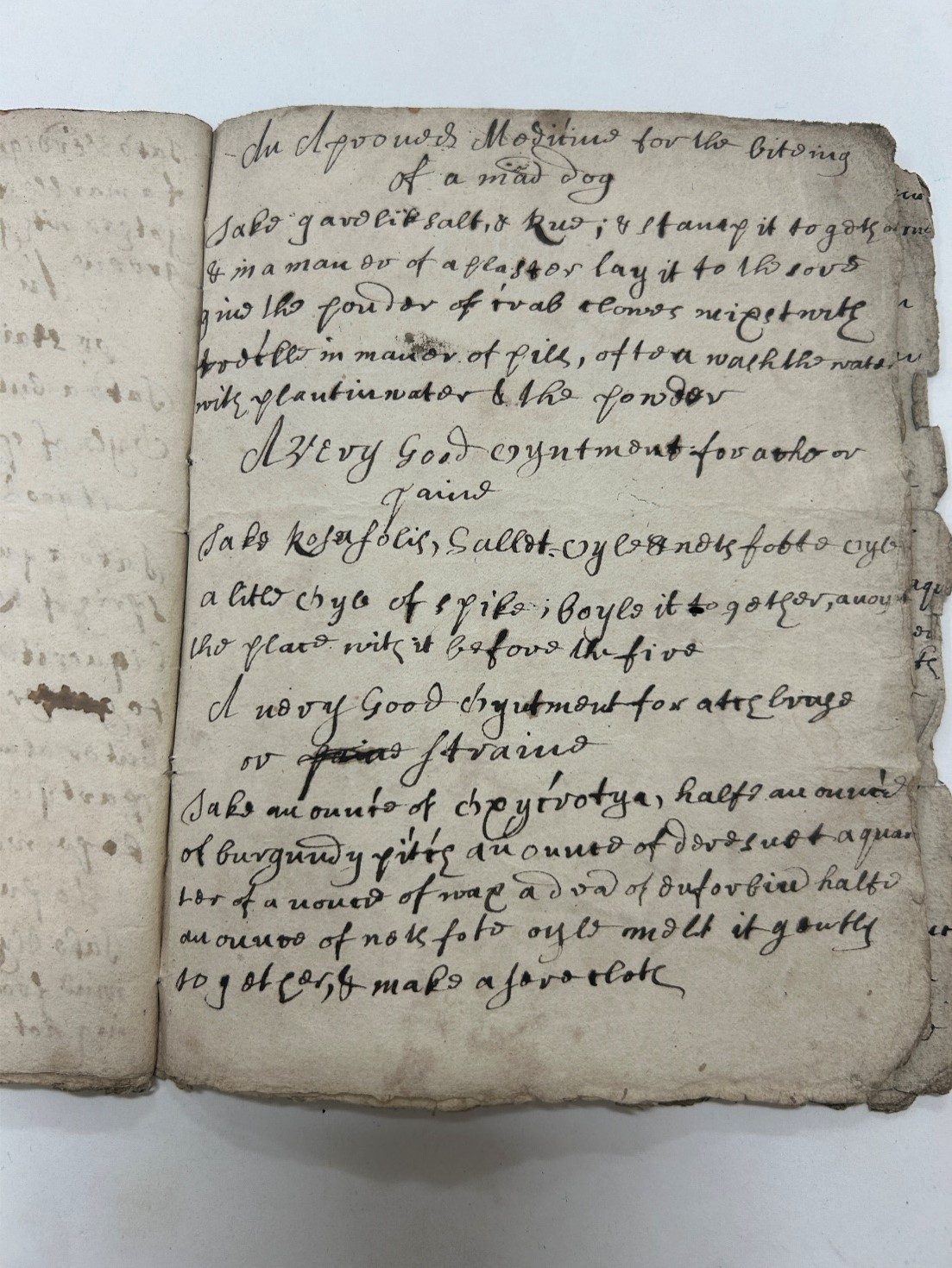 An old, weathered book page with handwritten text in faded ink. The script is cursive and ornate.